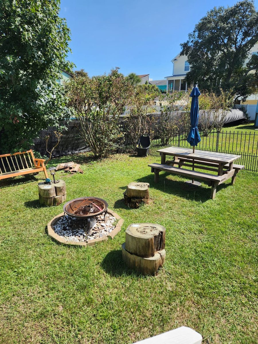 The fenced back yard with a fire pit and large picnic table
